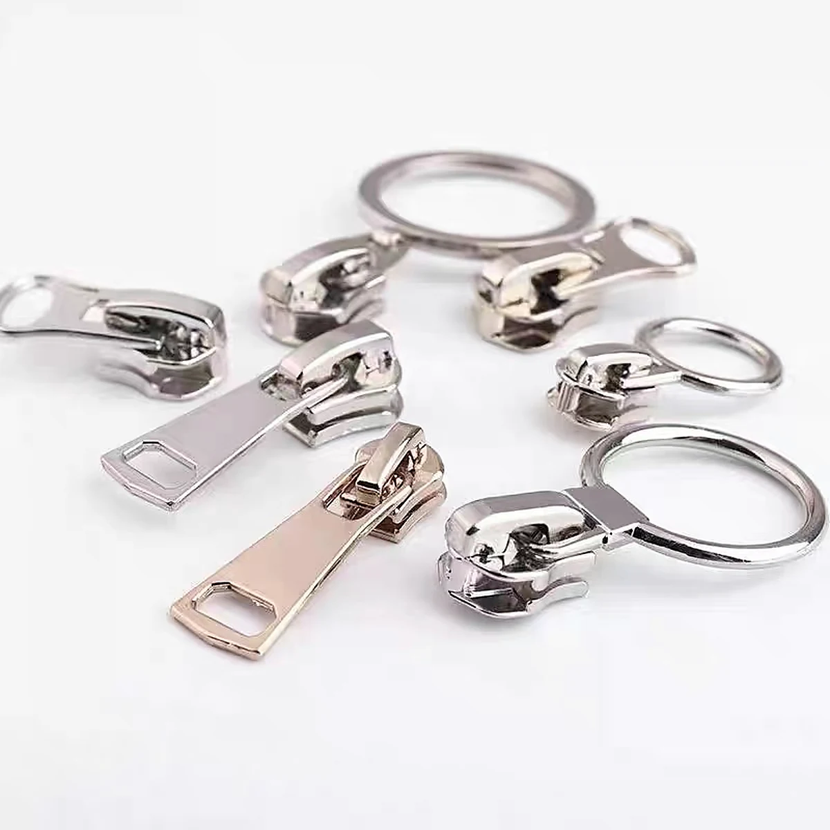 Metal zipper pullers arranged on a clean studio background